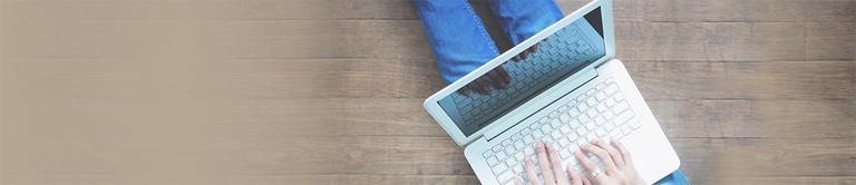 Downward view of a person typing on a laptop on the person's lap